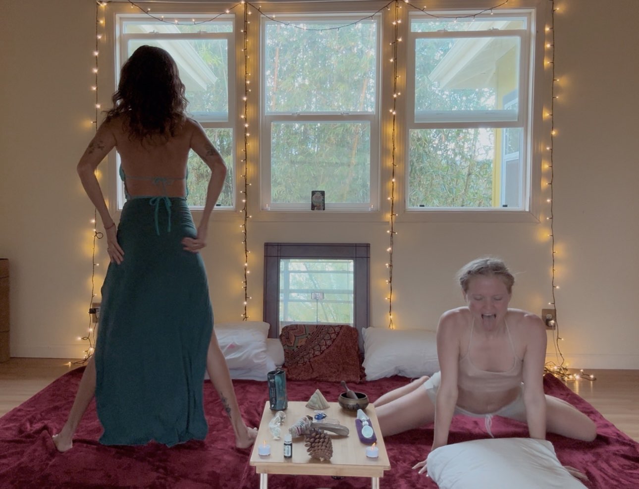 Women practicing embodiment on a red mat with ritual objects